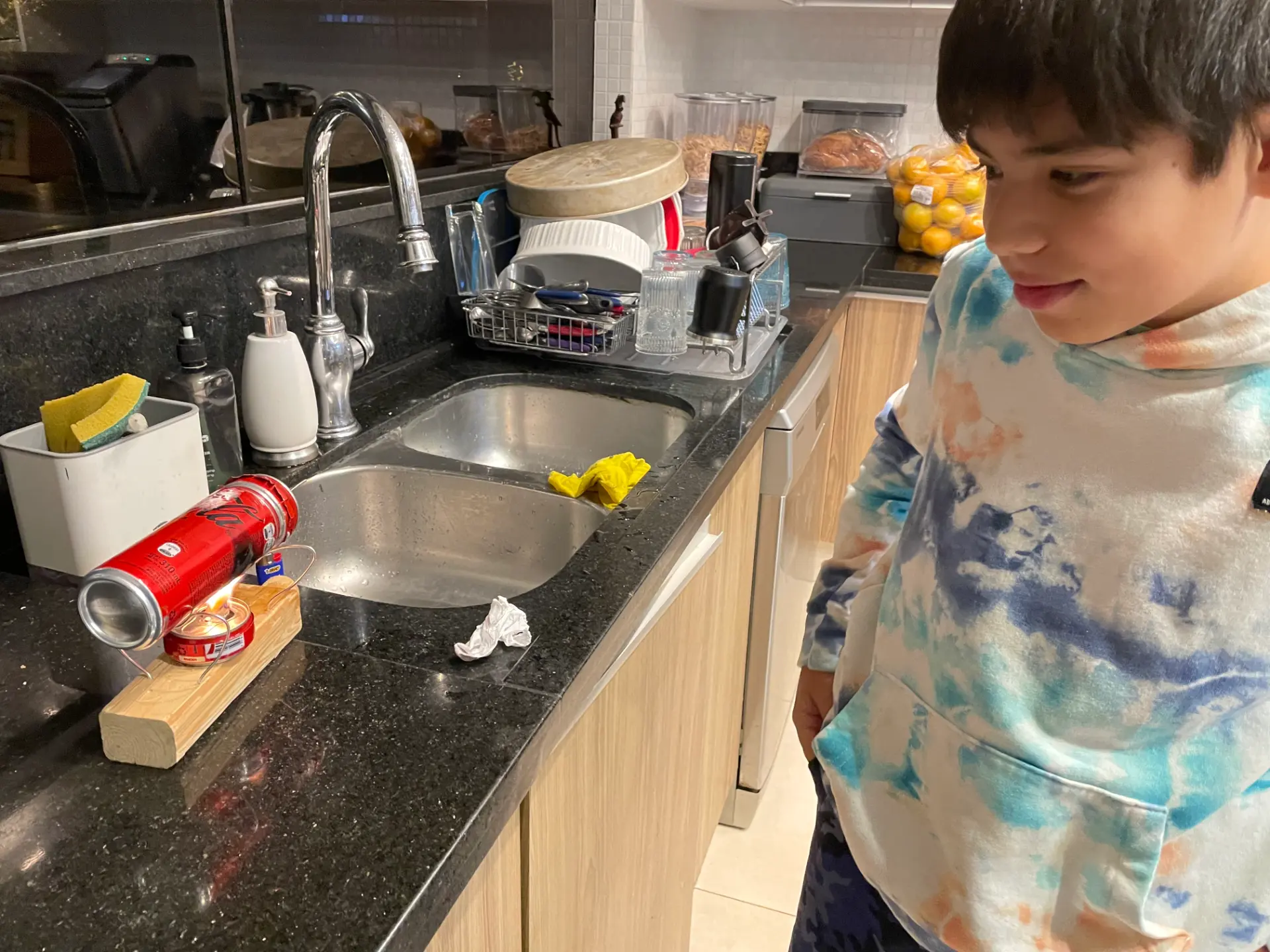 Niño observando el motor a vapor casero encendido sobre la mesada